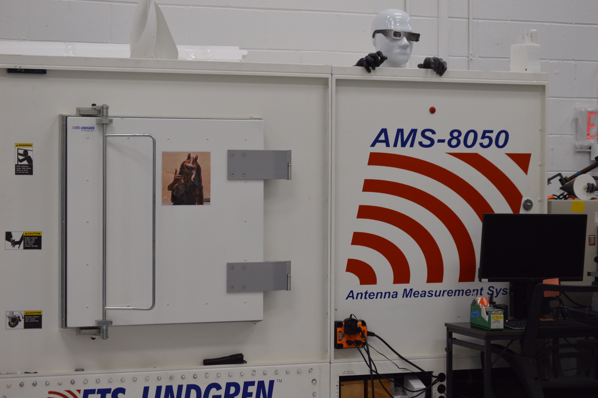 Exterior of fully anechoic antenna chamber with goofy mannequin head wearing 3D glasses sitting on top of it